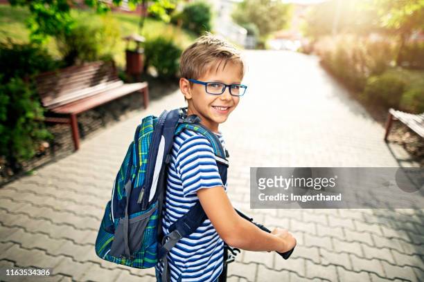 portrait of a little boy riding to school on push scooter - boys stock pictures, royalty-free photos & images
