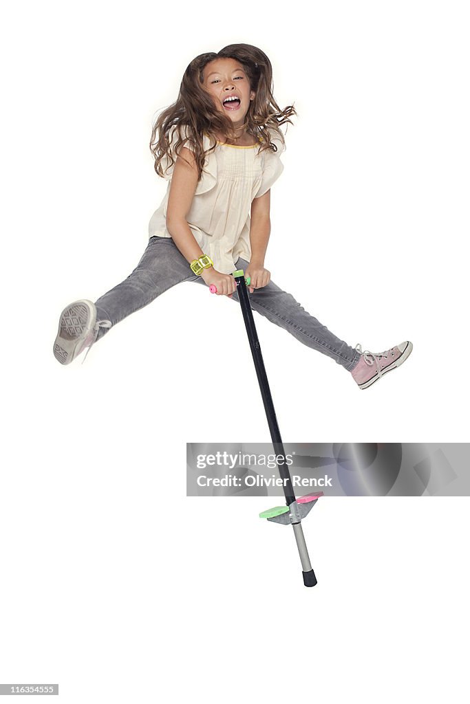 A young girl jumping on a pogo stick.