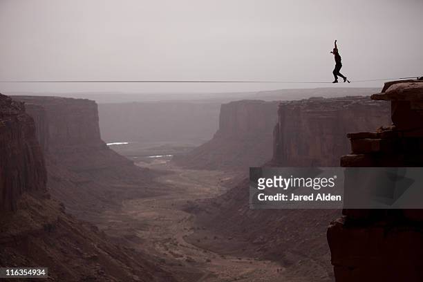 andy lewis working on a world record highline, three hundred and forty feet long, at the fruit bowl in moab, utah, usa. - hochseil stock-fotos und bilder