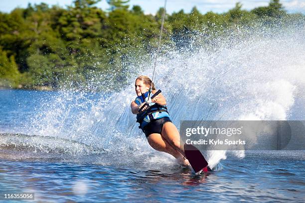 a female water skier rips a turn causing a huge water spray while skiing on cobbosseecontee lake near monmouth, maine. - wasserski stock-fotos und bilder