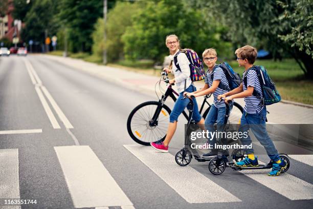 kinderen rijden naar school op de fiets en scooters - step stockfoto's en -beelden