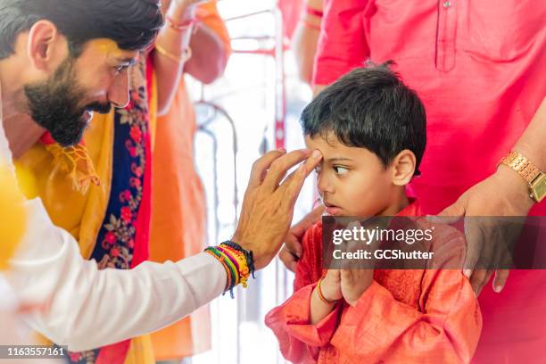 hindu priest doing "tilak" on the forehead of a boy - priest stock pictures, royalty-free photos & images