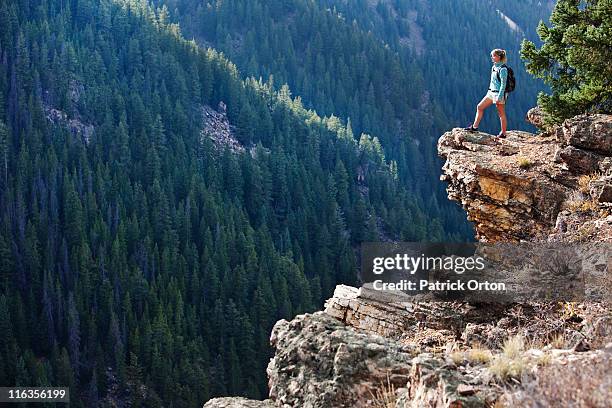 a young woman hiking takes a look over the edge of the canyon. - vail colorado stock-fotos und bilder