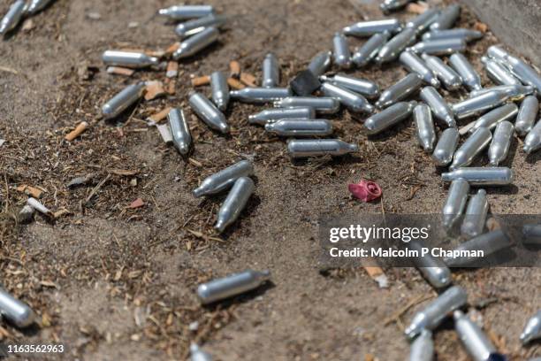 nitrous oxide n2o canisters litter london streets after being used as a recreational drug. - canister stock pictures, royalty-free photos & images