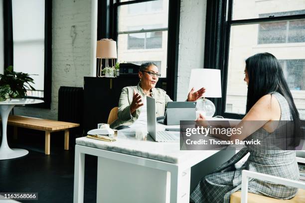 female financial advisor in discussion with mature female business owner at desk in office - black business owner stock-fotos und bilder