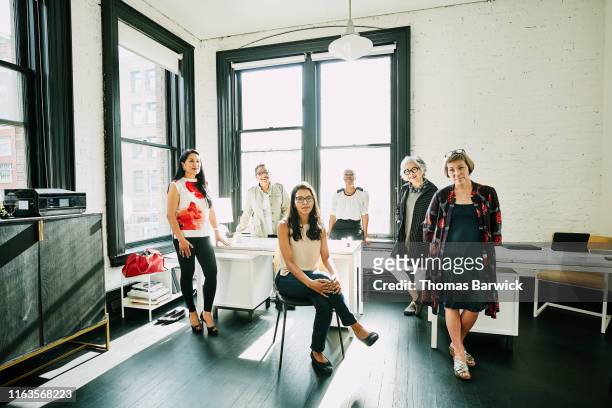 group portrait of businesswomen in creative office - sedersi posizione fisica foto e immagini stock