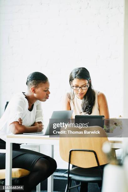 businesswomen reviewing project on digital tablet while working in office conference room - ipad vertical stock pictures, royalty-free photos & images