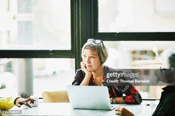 mature businesswoman listening during meeting with clients in office - wisdom knowledge modern stock-fotos und bilder