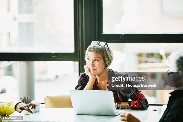 mature businesswoman listening during meeting with clients in office - selective focus foto e immagini stock