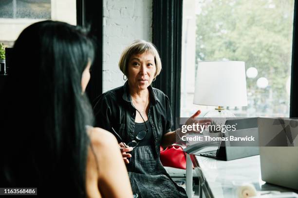 mature businesswomen discussing project at desk in creative office - indian old woman stock-fotos und bilder