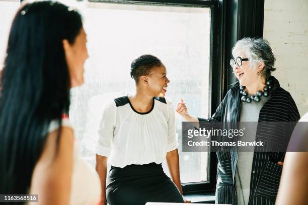 senior businesswoman laughing with colleague during meeting in creative office - etnias asiáticas e indias - fotografias e filmes do acervo