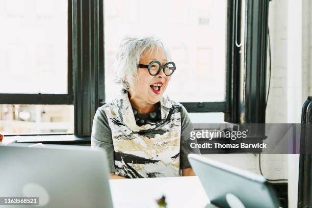 Laughing senior businesswoman in meeting in office conference room