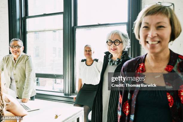 smiling businesswomen in creative office - intelligence community stock pictures, royalty-free photos & images