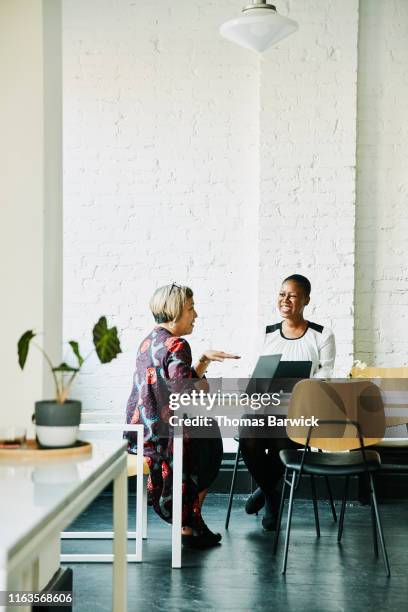 smiling businesswomen discussing project in office conference room - life advice stock pictures, royalty-free photos & images