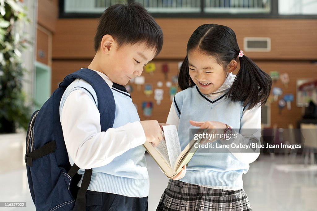 Young students huddle together reading a book