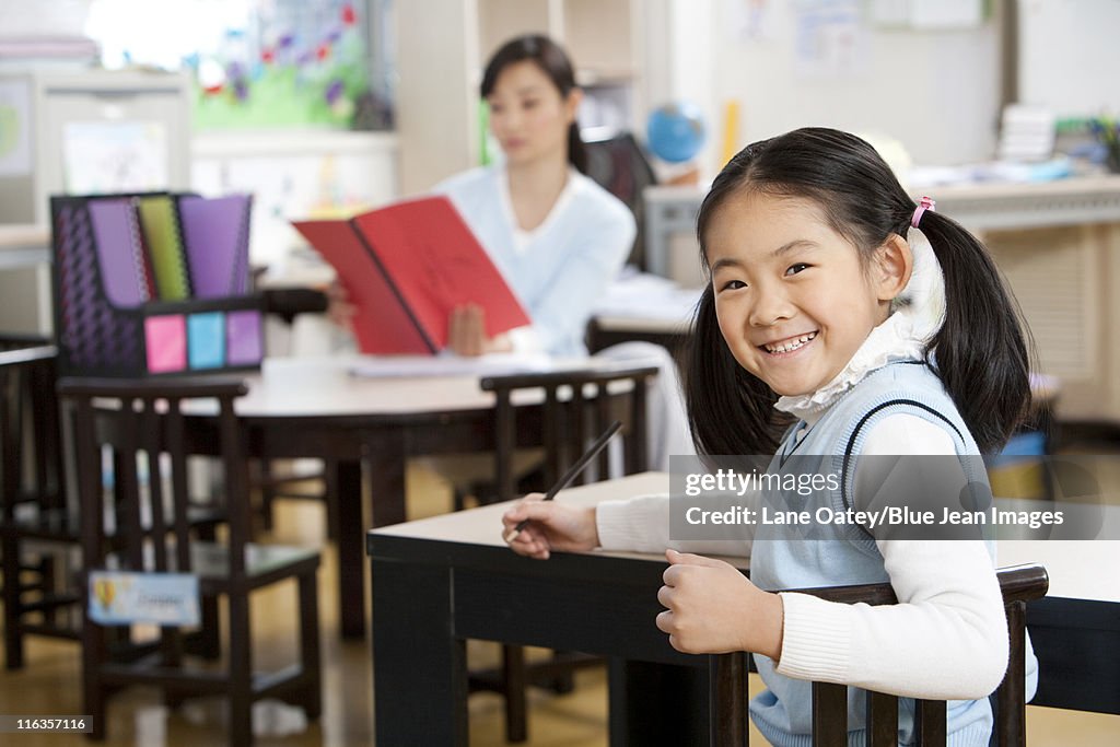 Young student looking over her shoulder smiling in class