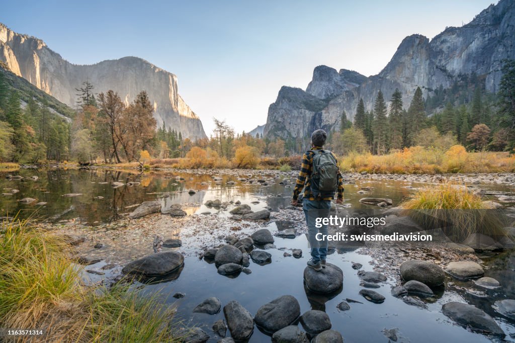 Young man contemplating Yosemite valley from the river, reflections on water surface