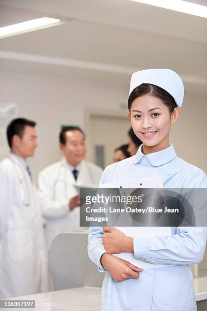 portrait of a confident nurse standing in front of her colleagues - nurse hat stock pictures, royalty-free photos & images