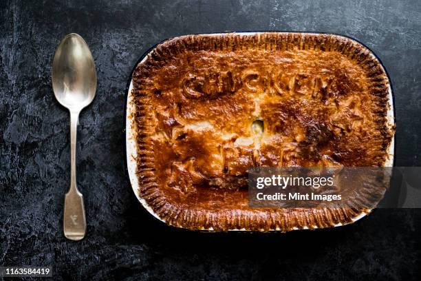 high angle close up of freshly baked chicken pie and silver spoon. - meat pie stock pictures, royalty-free photos & images