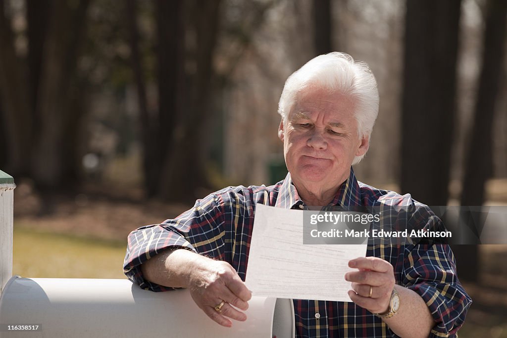 USA, Virginia, Richmond, senior man reading letter by mailbox