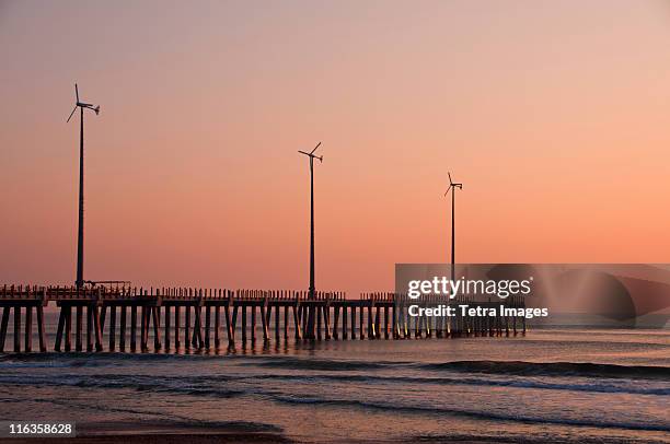 usa, north carolina, outer banks, kill devil hills, pier with wind turbines at sunset - kitty hawk stock-fotos und bilder