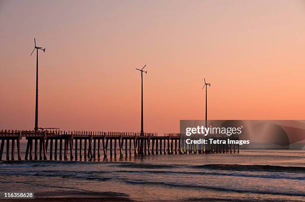 usa, north carolina, outer banks, kill devil hills, pier with wind turbines at sunset - kitty hawk beach stock pictures, royalty-free photos & images
