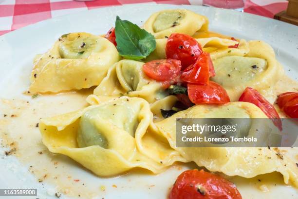 plate of tortelli with cherry tomatoes and basil - tortellini stock pictures, royalty-free photos & images