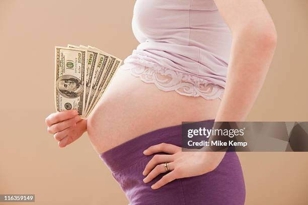 usa, utah, lehi, young pregnant woman holding money roll of dollars - money roll foto e immagini stock