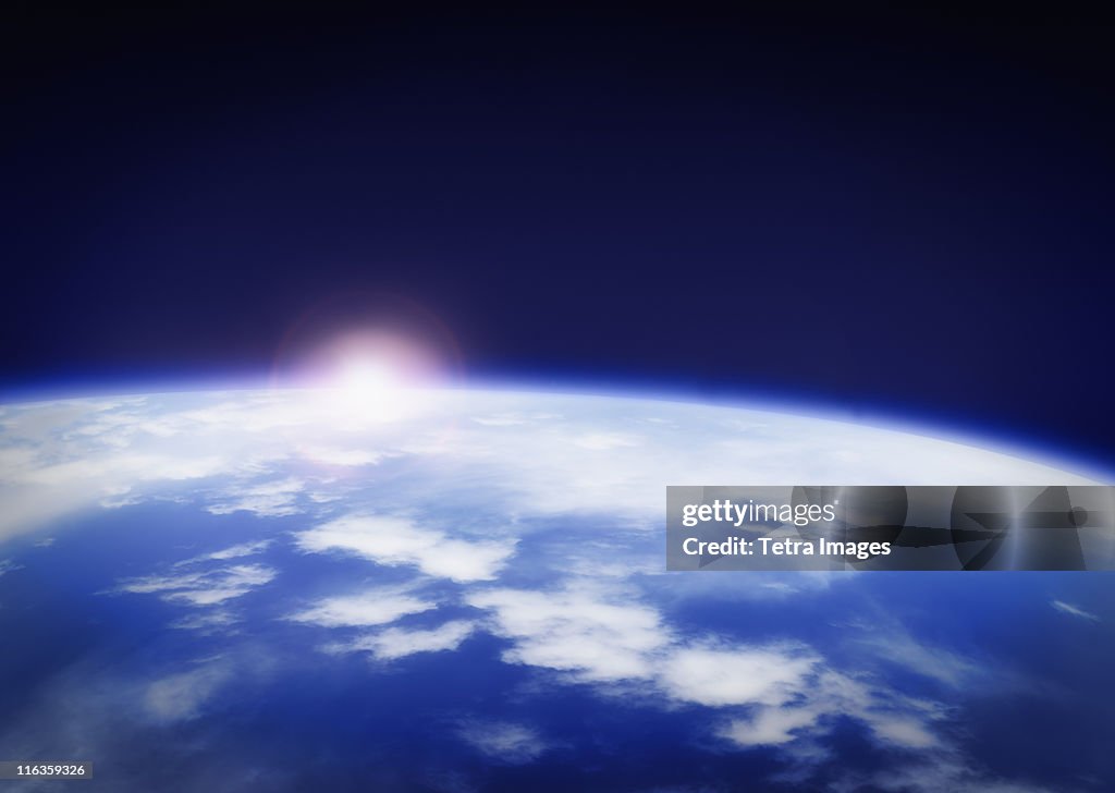 Space with rising sun above planet earth