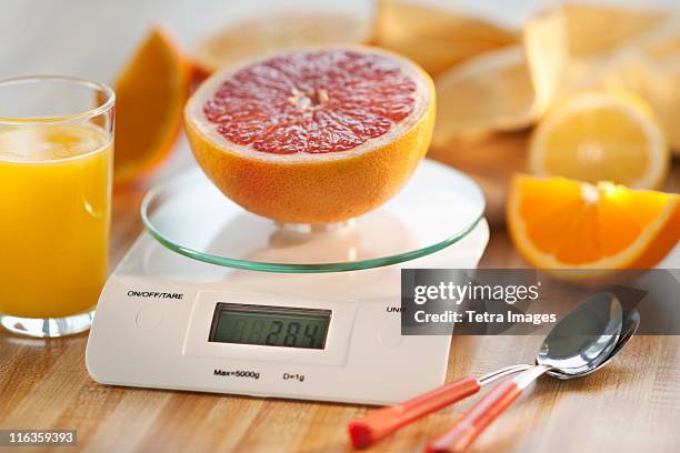 close up of half of orange on kitchen scale - köksvåg bildbanksfoton och bilder