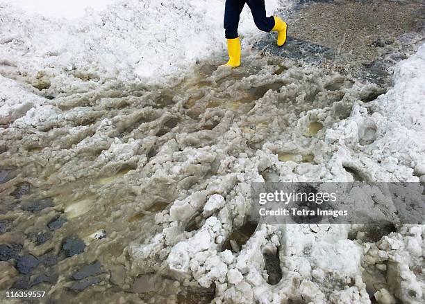 usa, new york, new york city, legs of person in yellow rubber boots walking in slush - tetra images stock-fotos und bilder