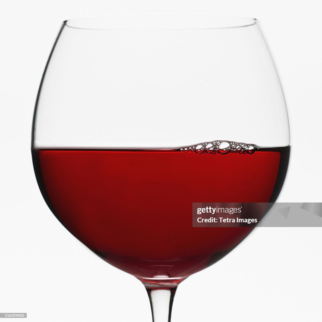 Close up of glass of red wine on white background