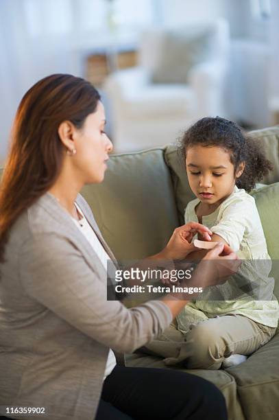 usa, new jersey, jersey city, mother applying bandaid on daughter's (6-7) arm - applying bandaid stock pictures, royalty-free photos & images