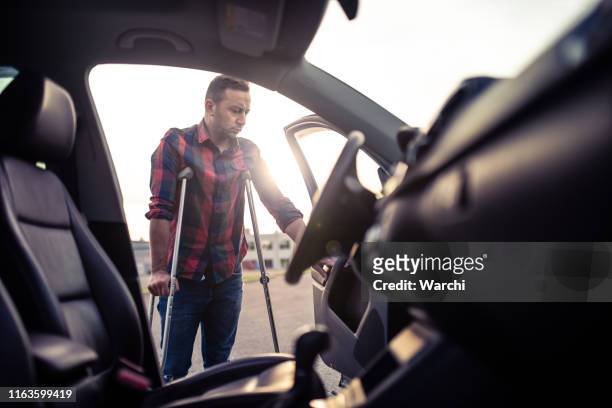 man using crutches is about to take the car - crutch stock pictures, royalty-free photos & images