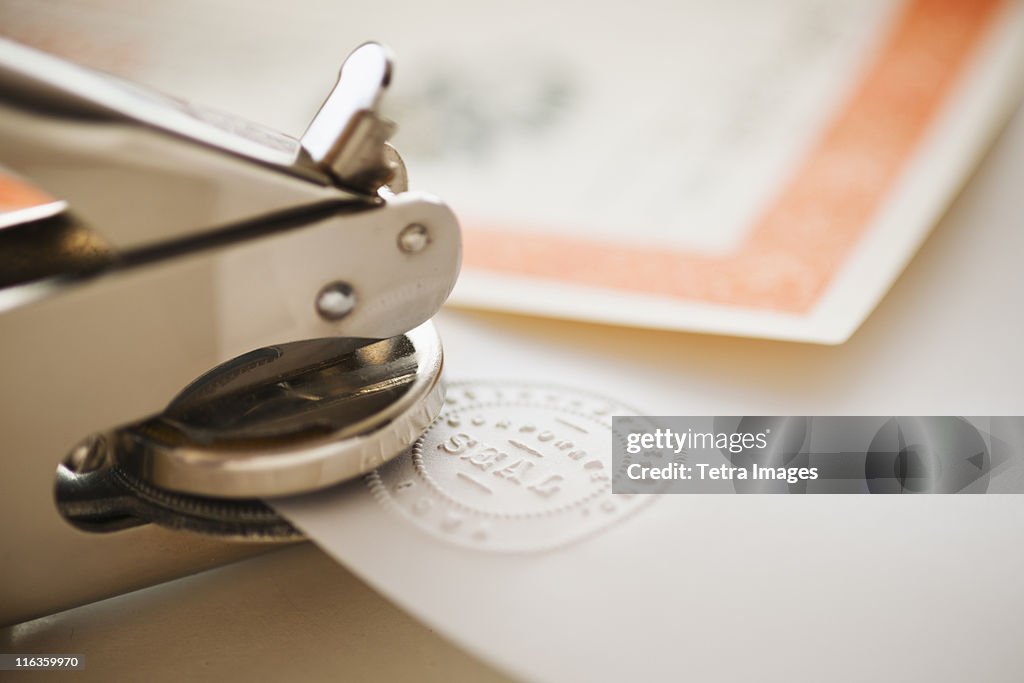 Close up of stamper making seal on paper