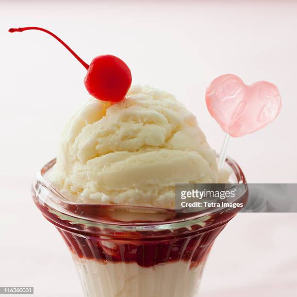close up of ice cream dessert with cherry on top and heart shaped decoration - cherry on top stock-fotos und bilder
