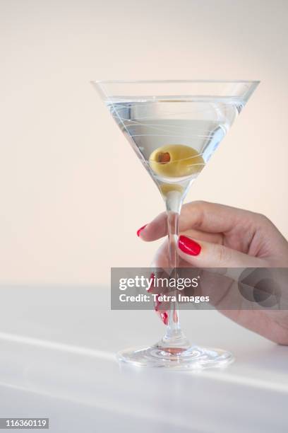 close up of woman's hand with nail polish holding martini glass with olive - woman holding martini glass stock pictures, royalty-free photos & images