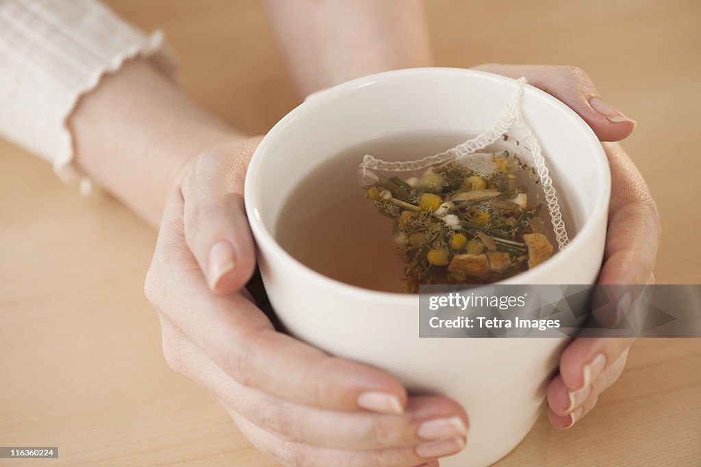 Woman holding cup with chamomile tea