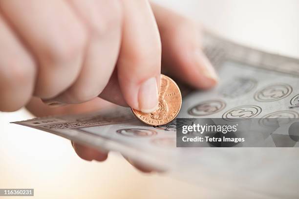 studio shot of woman scratching lottery ticket - lottery ticket stock pictures, royalty-free photos & images