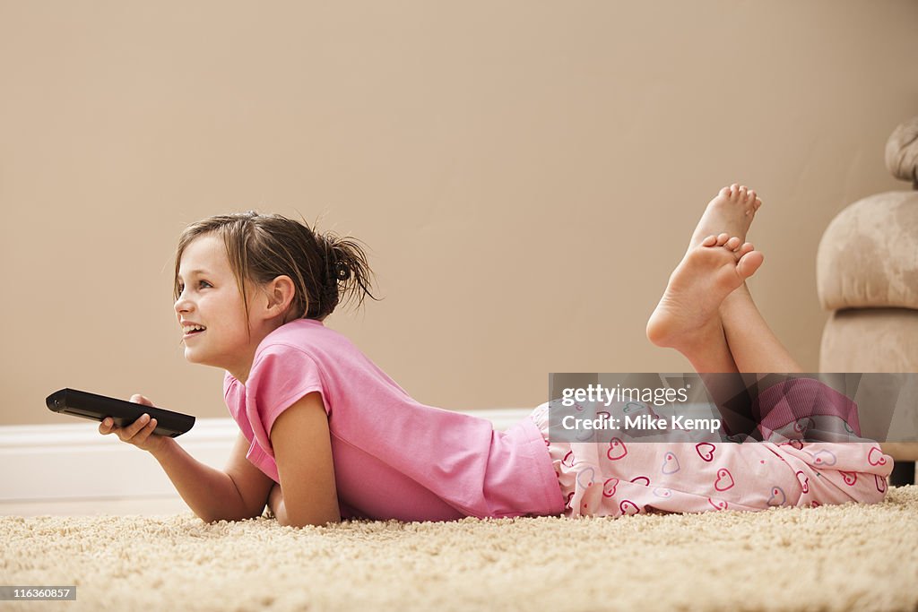 USA, Utah, Lehi, girl (10-11) lying on floor holding remote control