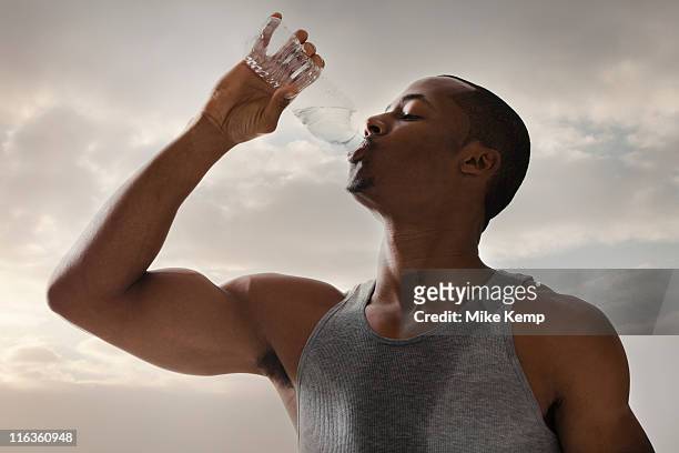 usa, utah, salt lake city, athlete young man drinking water form bottle, cloudy sky in background - bottle water sport stock-fotos und bilder