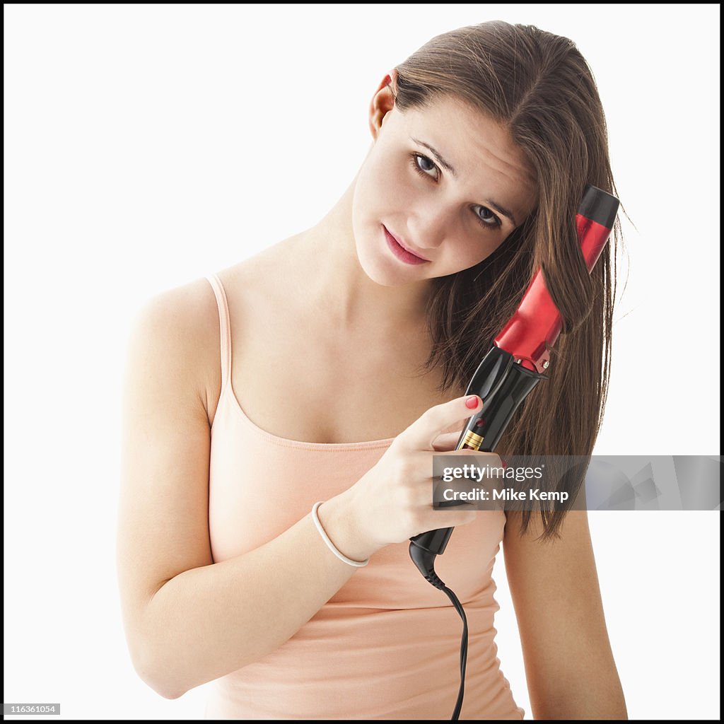 Studio portrait of young woman curling hair