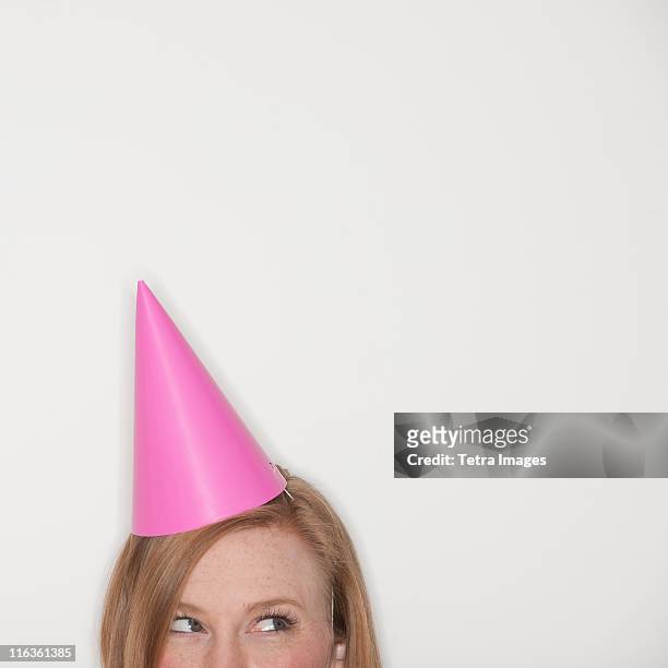 studio shot of woman wearing pink party hat - party hat stock pictures, royalty-free photos & images