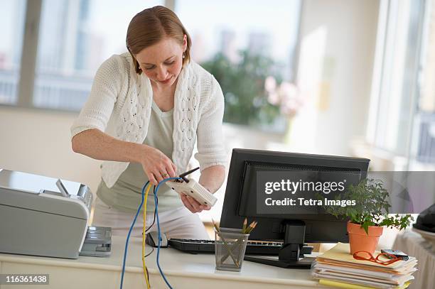 usa, new jersey, jersey city, woman installing router at home office - internet router stock pictures, royalty-free photos & images