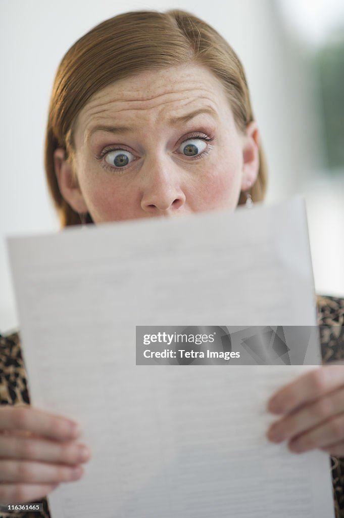 USA, New Jersey, Jersey City, woman reading document looking surprised