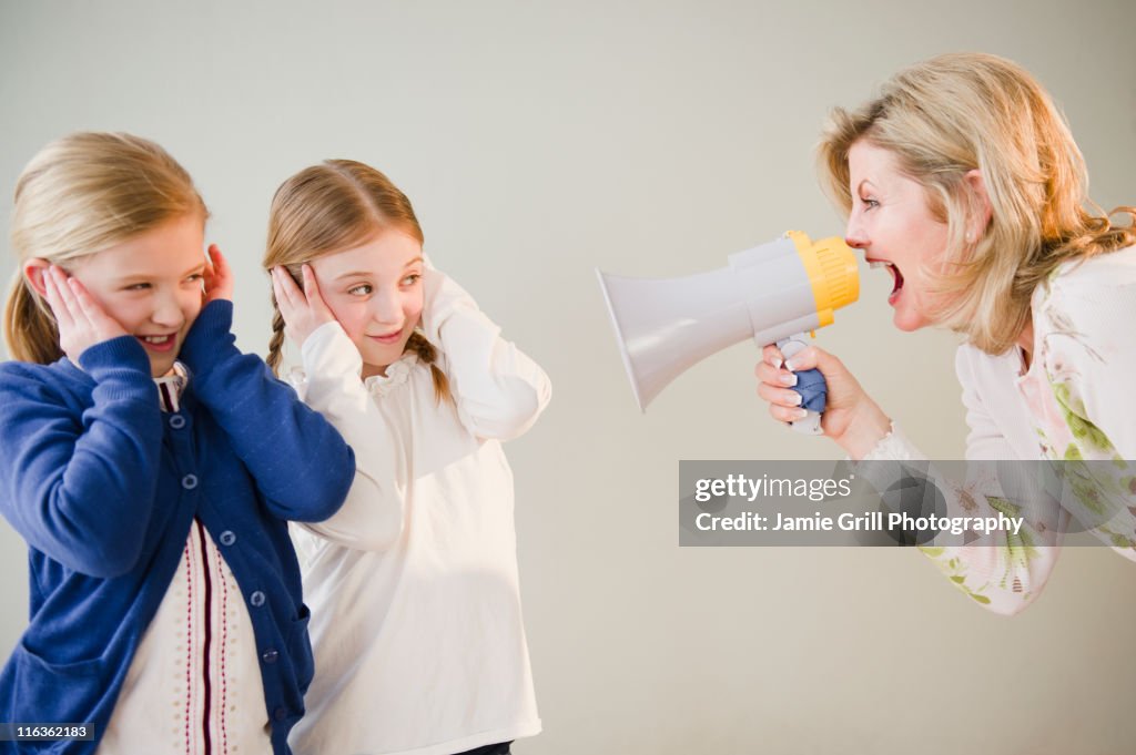USA, Jersey City, New Jersey, mother shouting at daughters (8-11) through bullhorn