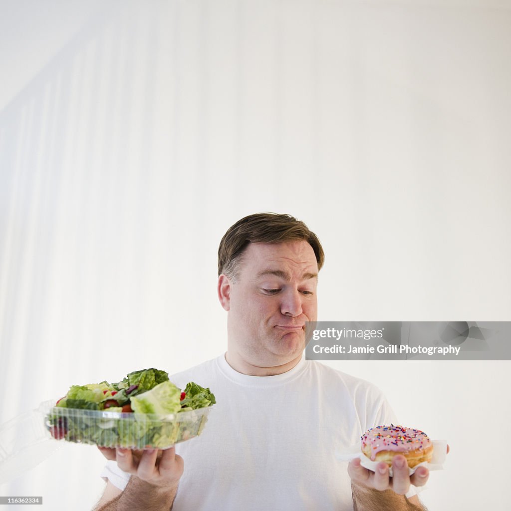 USA, Jersey City, New Jersey, man comparing donut and salad