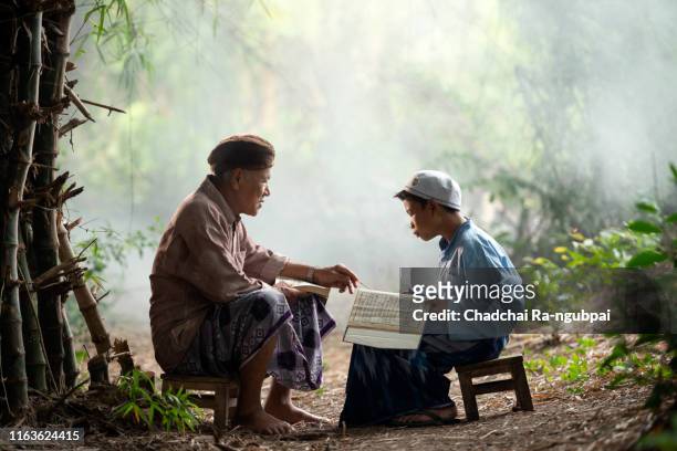 asian muslim men are teaching muslim children to read al-qur'an to believe that islam in rural areas in bali, indonesia. - child praying school stock pictures, royalty-free photos & images