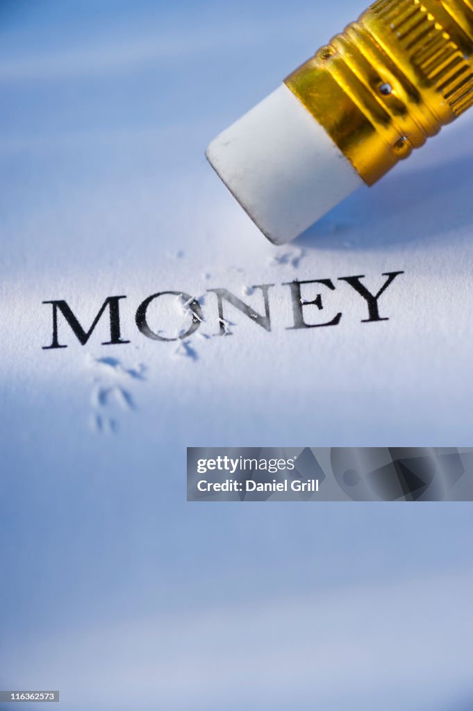 Studio shot of pencil erasing the word money from piece of paper