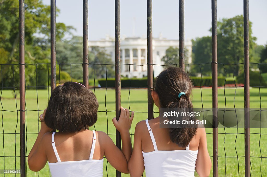 USA, Washington DC, two girls looking at White House through fence